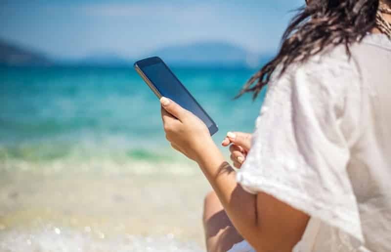 Menina usando o celular em praia de Cancún