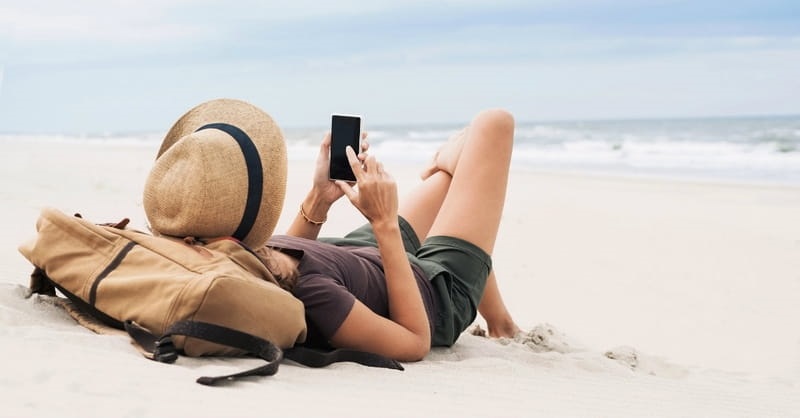 Menina usando celular em praia