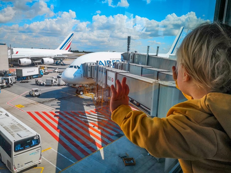 Criança olhando pela janela os aviões em aeroporto