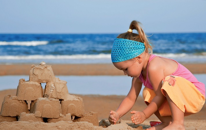 Menina brincando na areia da praia